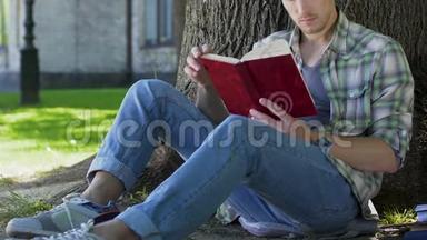 大学生男学生坐在树下，读书促进自我发展